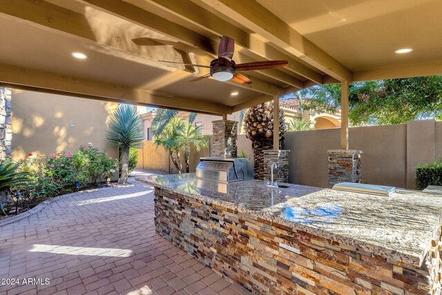 view of patio with ceiling fan, exterior kitchen, a grill, and fence