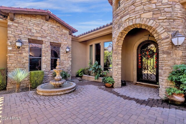 property entrance with stone siding, a tile roof, and stucco siding