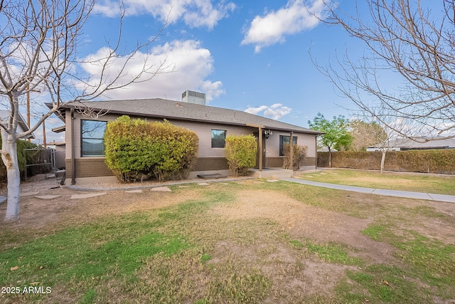 back of house with brick siding, a lawn, and fence