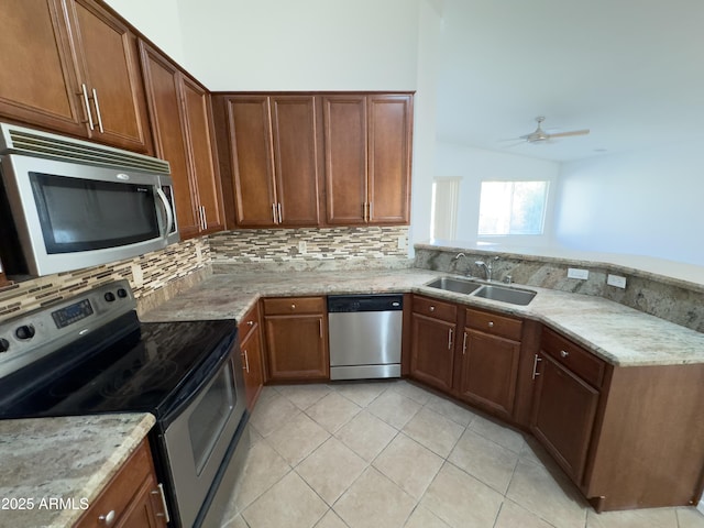 kitchen with a sink, a peninsula, stainless steel appliances, and backsplash