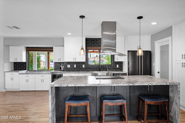 8730 E Montecito Ave, Scottsdale, AZ 85251 - kitchen with freestanding refrigerator, island range hood, beverage cooler, light wood finished floors, and recessed lighting