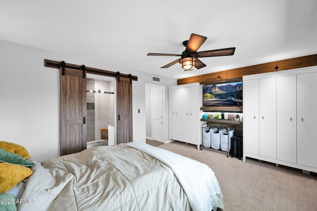 8730 E Montecito Ave, Scottsdale, AZ 85251 - bedroom with a barn door, light colored carpet, ceiling fan, connected bathroom, and multiple closets