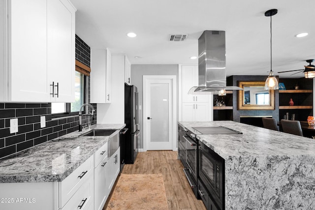8730 E Montecito Ave, Scottsdale, AZ 85251 - kitchen with black microwave, island exhaust hood, a sink, freestanding refrigerator, and white cabinets