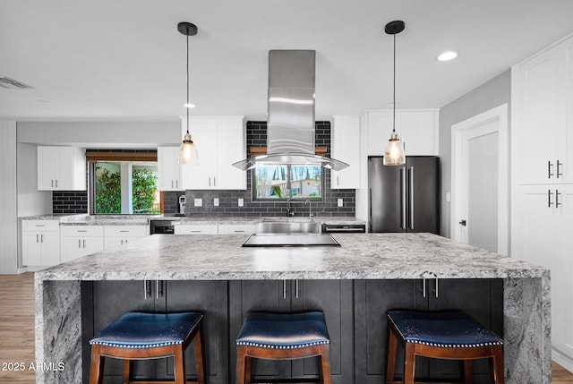 8730 E Montecito Ave, Scottsdale, AZ 85251 - kitchen featuring freestanding refrigerator, island exhaust hood, light wood-style floors, decorative backsplash, and white cabinets