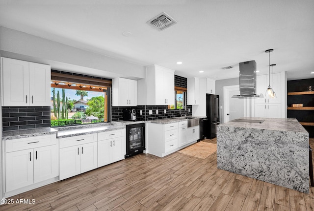 8730 E Montecito Ave, Scottsdale, AZ 85251 - kitchen with beverage cooler, island exhaust hood, black appliances, backsplash, and recessed lighting
