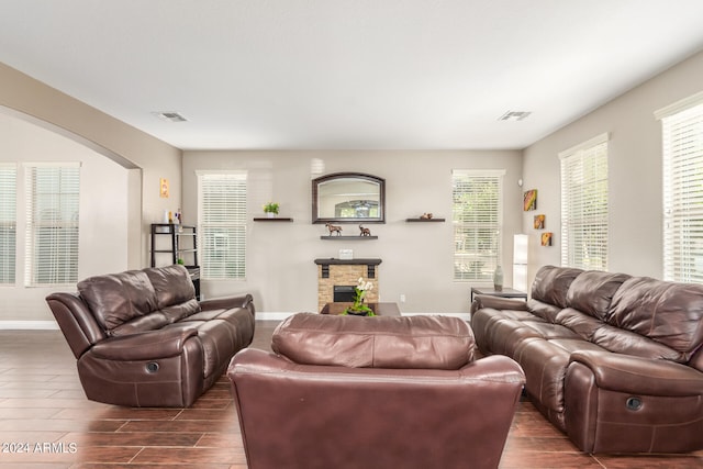 living room with a stone fireplace and plenty of natural light