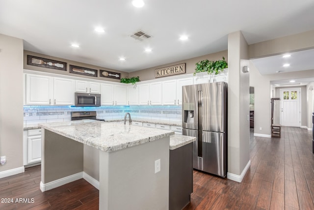 kitchen featuring appliances with stainless steel finishes, a kitchen island with sink, white cabinets, and light stone counters