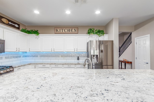 kitchen with light stone countertops, white cabinetry, appliances with stainless steel finishes, and sink