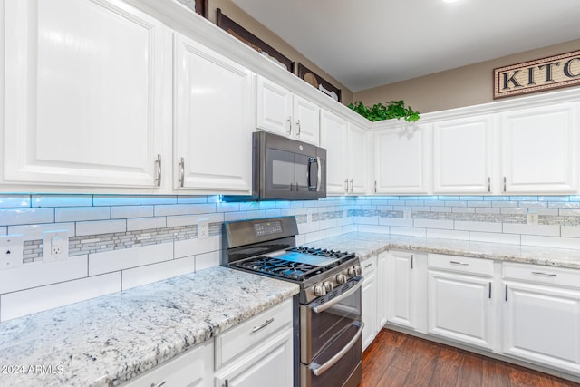 kitchen with double oven range, dark hardwood / wood-style floors, light stone counters, white cabinets, and decorative backsplash