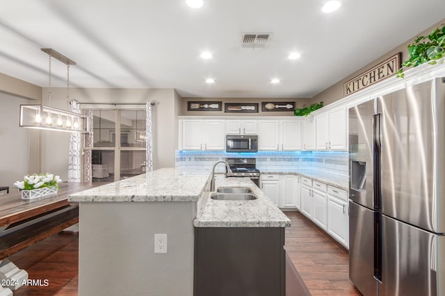 kitchen with appliances with stainless steel finishes, a kitchen island with sink, hanging light fixtures, and white cabinets