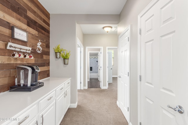 hallway with light carpet and wood walls