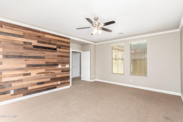 carpeted empty room with wooden walls, ornamental molding, and ceiling fan