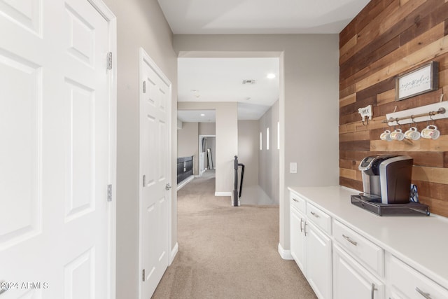 hall with wooden walls and light colored carpet