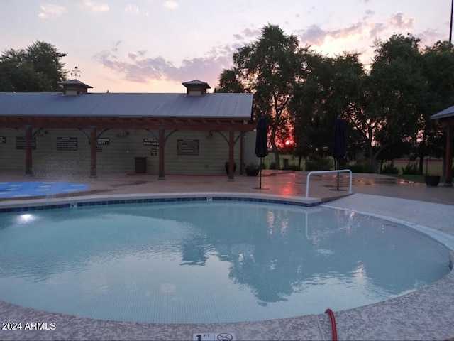 pool at dusk with a gazebo and a patio area