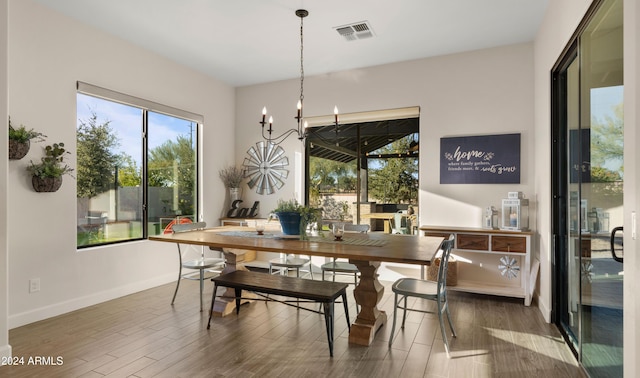 dining space with dark wood-type flooring and an inviting chandelier