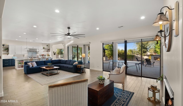 living room featuring light wood-type flooring, ceiling fan, and sink