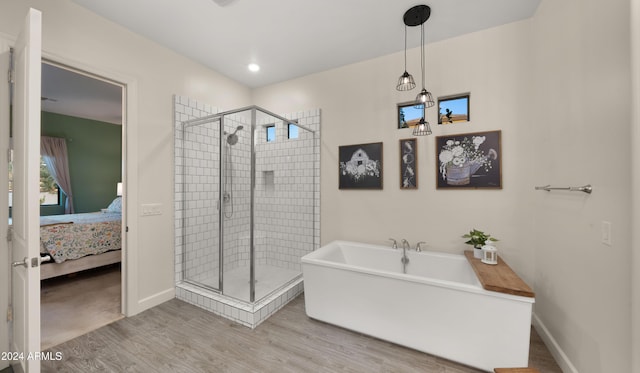 bathroom with shower with separate bathtub and wood-type flooring