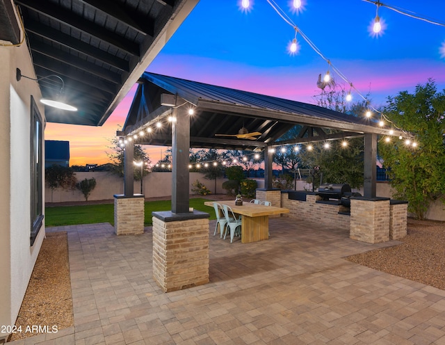 patio terrace at dusk with ceiling fan, a gazebo, and area for grilling