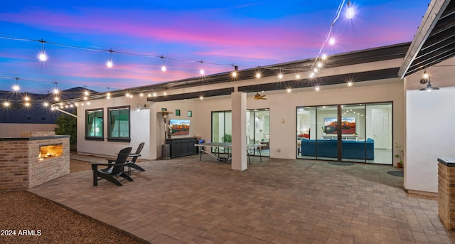 patio terrace at dusk featuring exterior fireplace and exterior kitchen