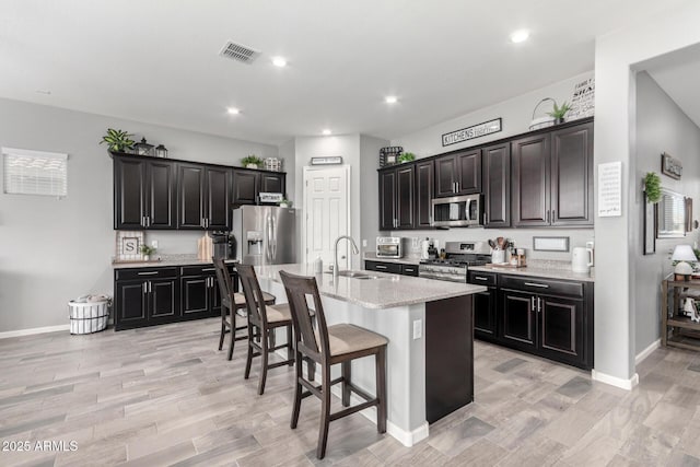 kitchen with a breakfast bar area, recessed lighting, visible vents, appliances with stainless steel finishes, and a sink