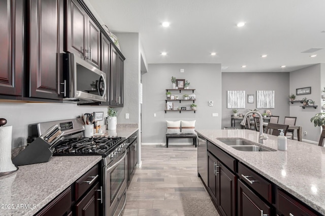 kitchen with appliances with stainless steel finishes, recessed lighting, a sink, and light stone counters