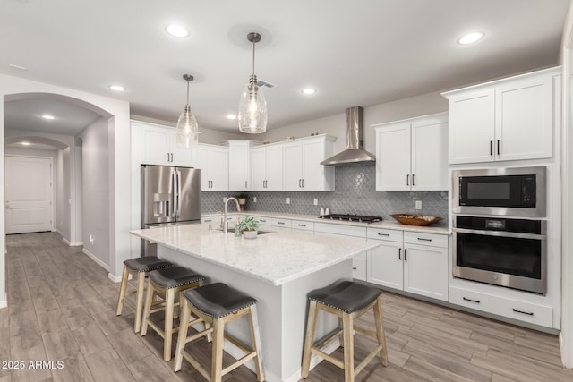 3474 W Dreamy Draw Dr, Queen Creek, AZ 85144 - kitchen with stainless steel appliances, wall chimney exhaust hood, a sink, a kitchen breakfast bar, and light wood-style floors