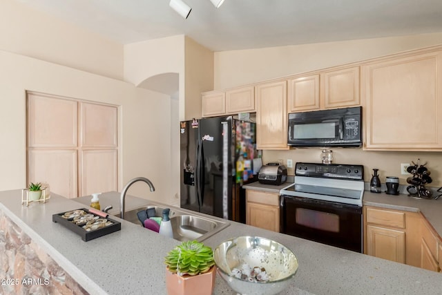 kitchen featuring lofted ceiling, light brown cabinets, a sink, a peninsula, and black appliances