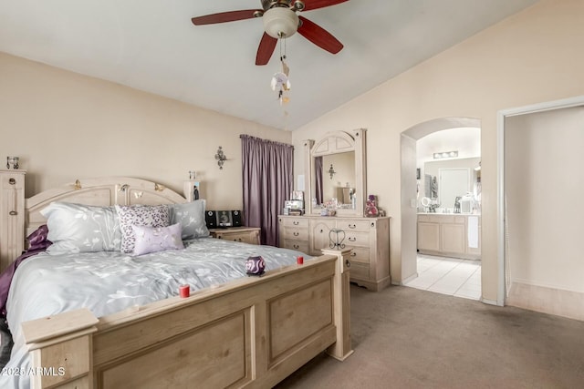 bedroom with arched walkways, light carpet, connected bathroom, vaulted ceiling, and ceiling fan
