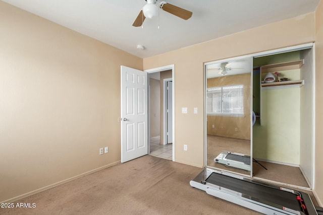 unfurnished bedroom featuring baseboards, a ceiling fan, a closet, and light colored carpet