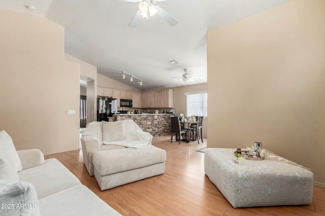 living room featuring light wood finished floors, visible vents, lofted ceiling, ceiling fan, and rail lighting