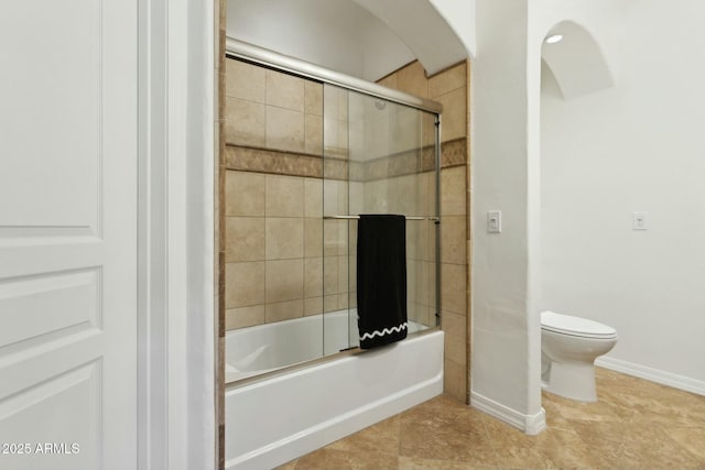 full bath featuring baseboards, combined bath / shower with glass door, and toilet
