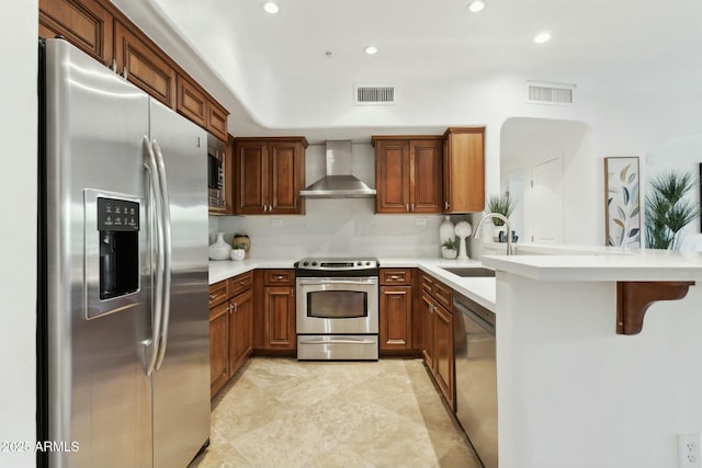 kitchen with visible vents, a peninsula, appliances with stainless steel finishes, and wall chimney range hood