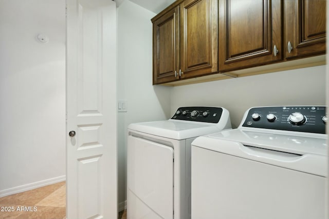 washroom with baseboards, cabinet space, and washer and dryer