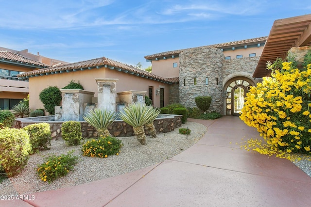 view of front of home with stucco siding, stone siding, and a tile roof