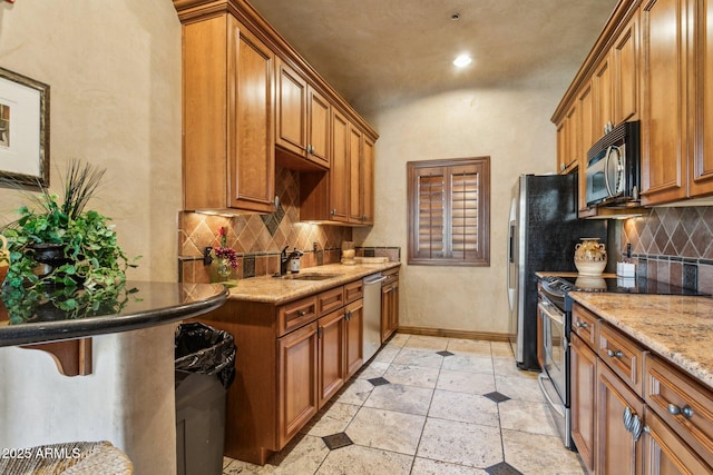kitchen featuring a sink, appliances with stainless steel finishes, brown cabinetry, and backsplash