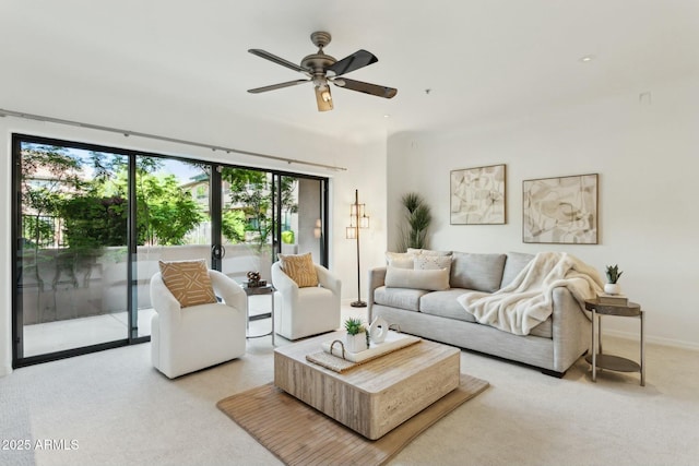 living room featuring baseboards, a ceiling fan, a healthy amount of sunlight, and light carpet