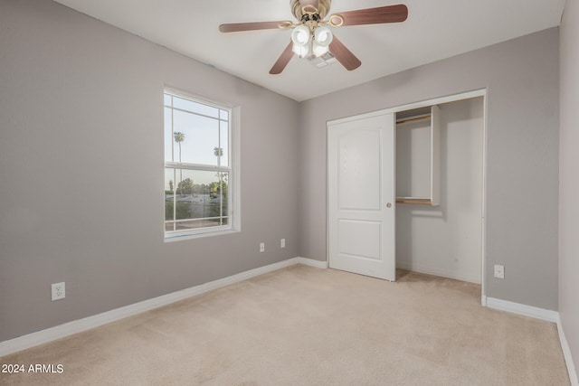 unfurnished bedroom featuring ceiling fan, a closet, and light colored carpet