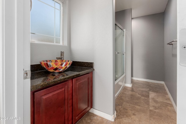 bathroom with bath / shower combo with glass door and vanity