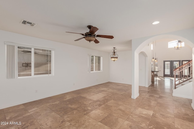 spare room with ceiling fan with notable chandelier