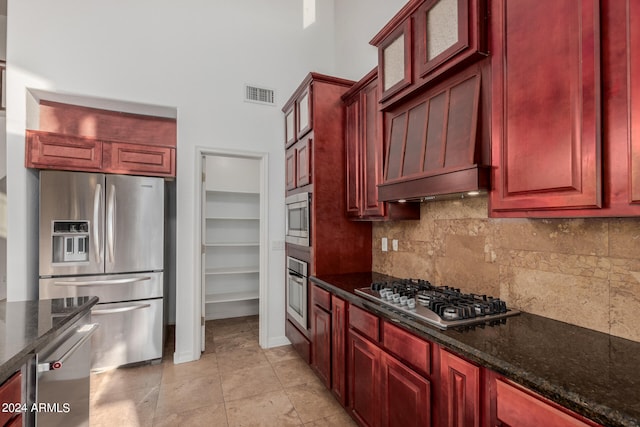 kitchen with stainless steel appliances, dark stone counters, decorative backsplash, and custom range hood