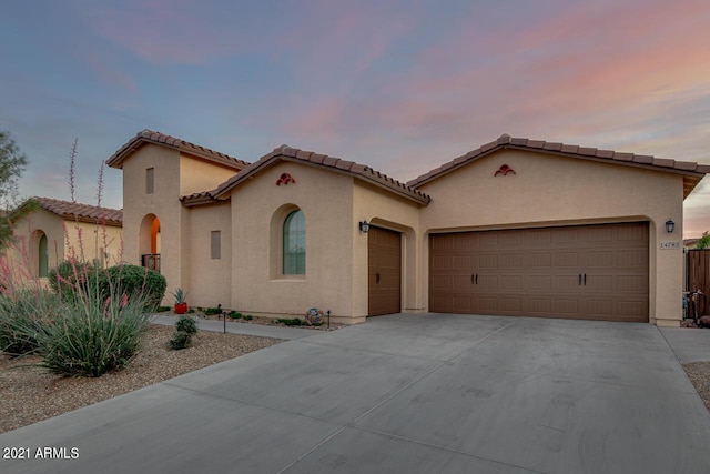 mediterranean / spanish home with a garage, driveway, and stucco siding