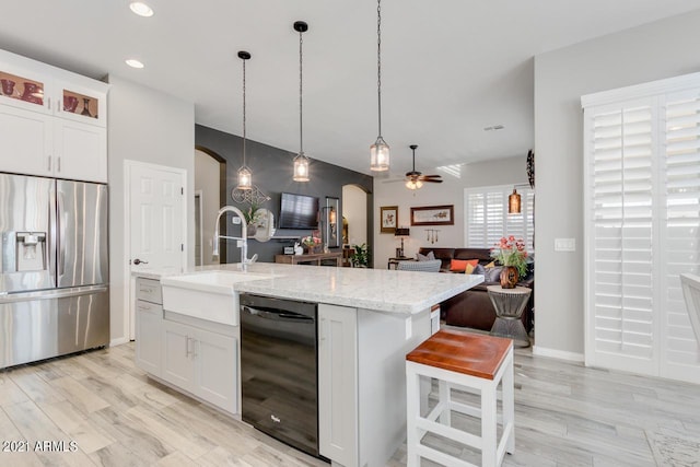 kitchen with black dishwasher, stainless steel fridge, arched walkways, glass insert cabinets, and open floor plan