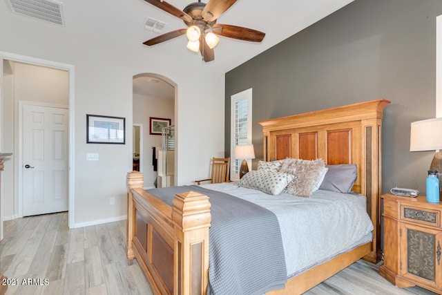 bedroom featuring light wood-type flooring, arched walkways, visible vents, and baseboards