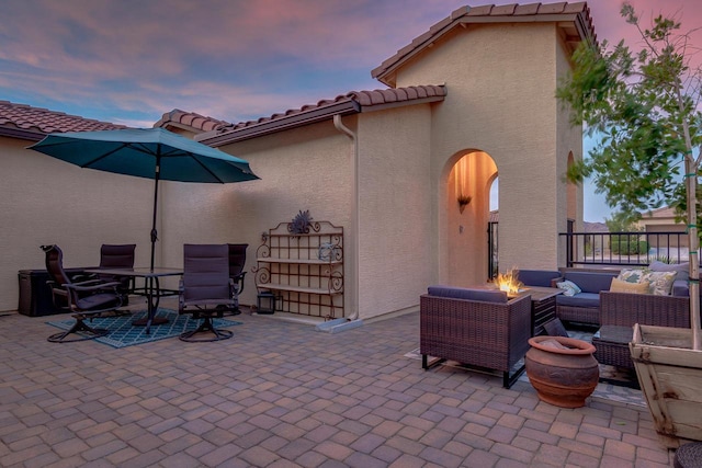 patio terrace at dusk with an outdoor living space with a fire pit