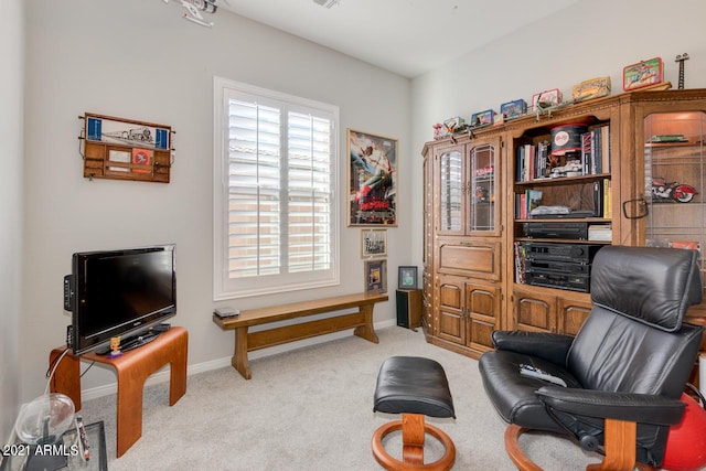 living area featuring light carpet and baseboards