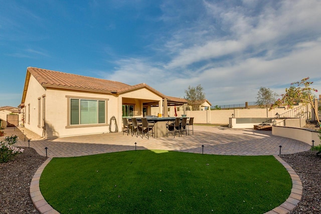 back of property featuring a fenced backyard, outdoor dry bar, a tiled roof, a lawn, and stucco siding