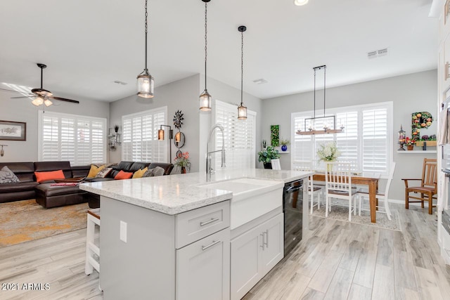 kitchen with hanging light fixtures, white cabinetry, open floor plan, and an island with sink