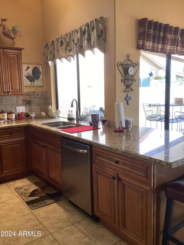 kitchen with dishwasher, stone countertops, light tile patterned floors, tasteful backsplash, and sink