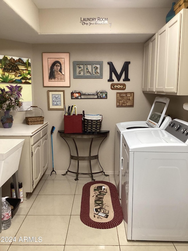 laundry room featuring light tile patterned floors, cabinets, and washer and dryer