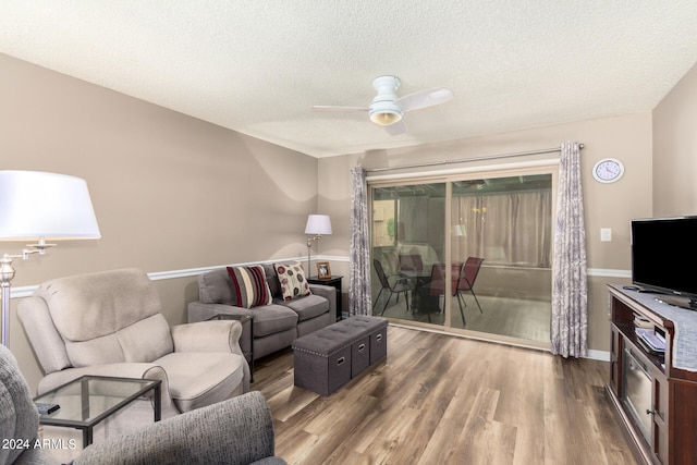 living room with ceiling fan, a textured ceiling, and dark hardwood / wood-style floors